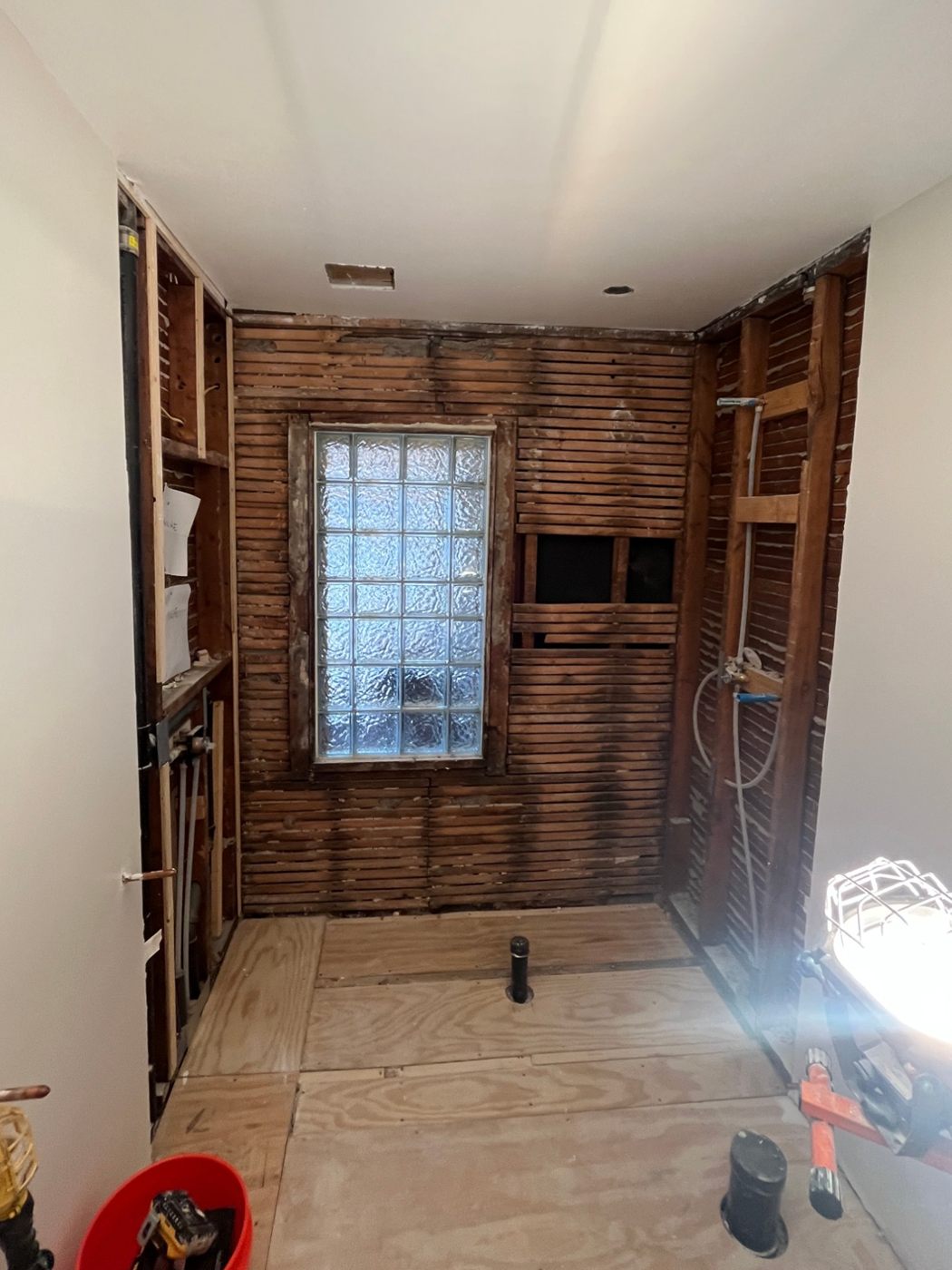 The same shower stripped to wood lath and a glass block window, before tiling